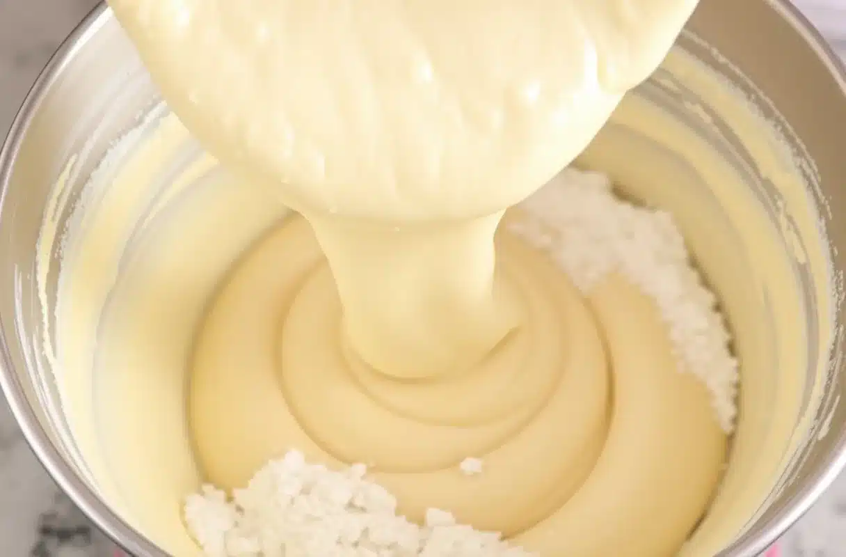 Cake batter being poured into a greased mixing bowl for baking